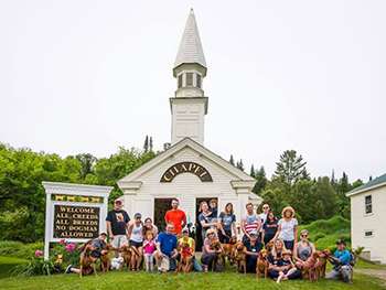 A group of people and their dogs posing in front of Dog Chapel