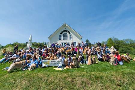 A large group of people posing together outside the Stephen Huneck art gallery